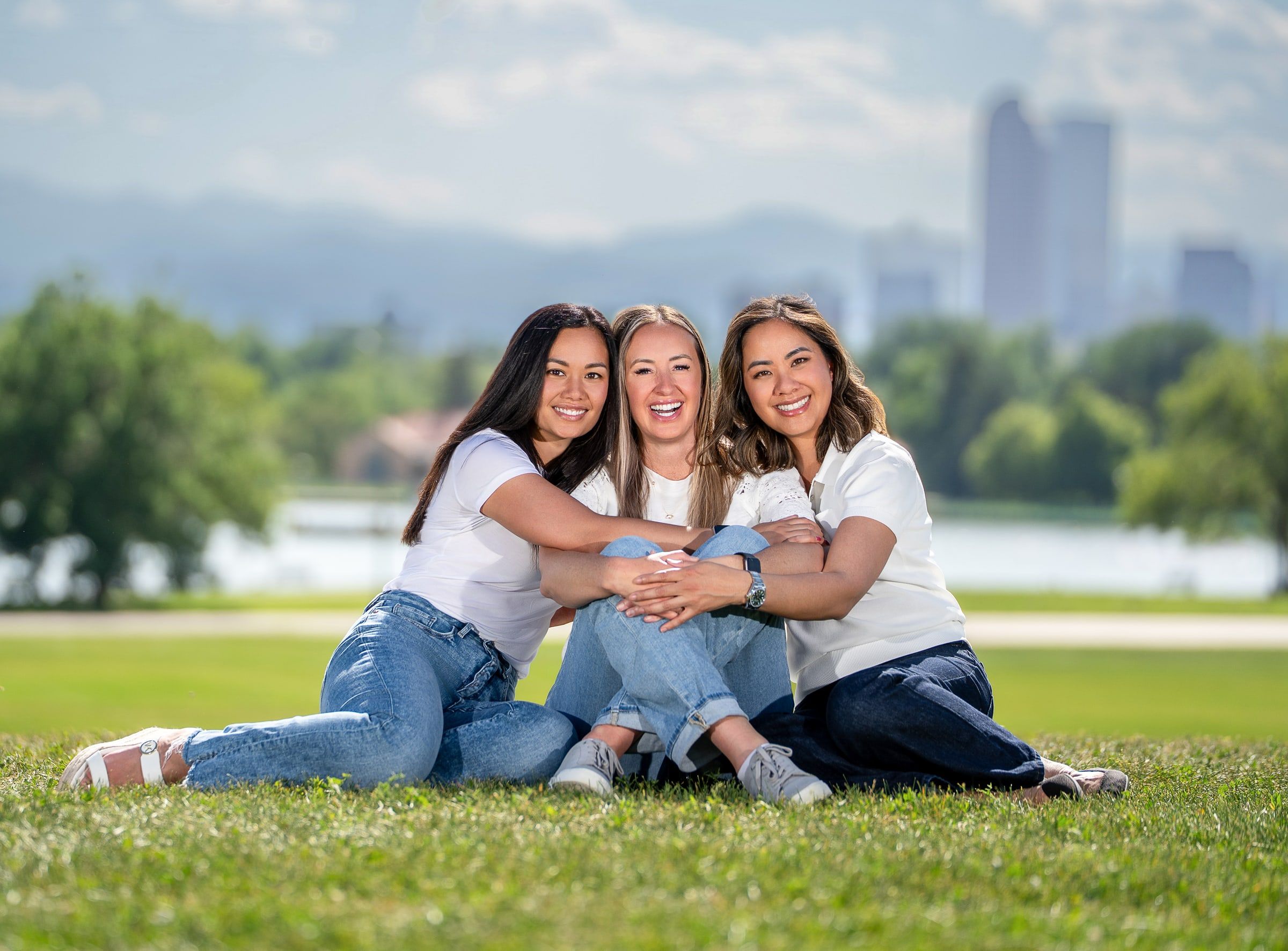 Three Cherry Creek Dental Spa doctors seated together outdoors with the Denver skyline behind them